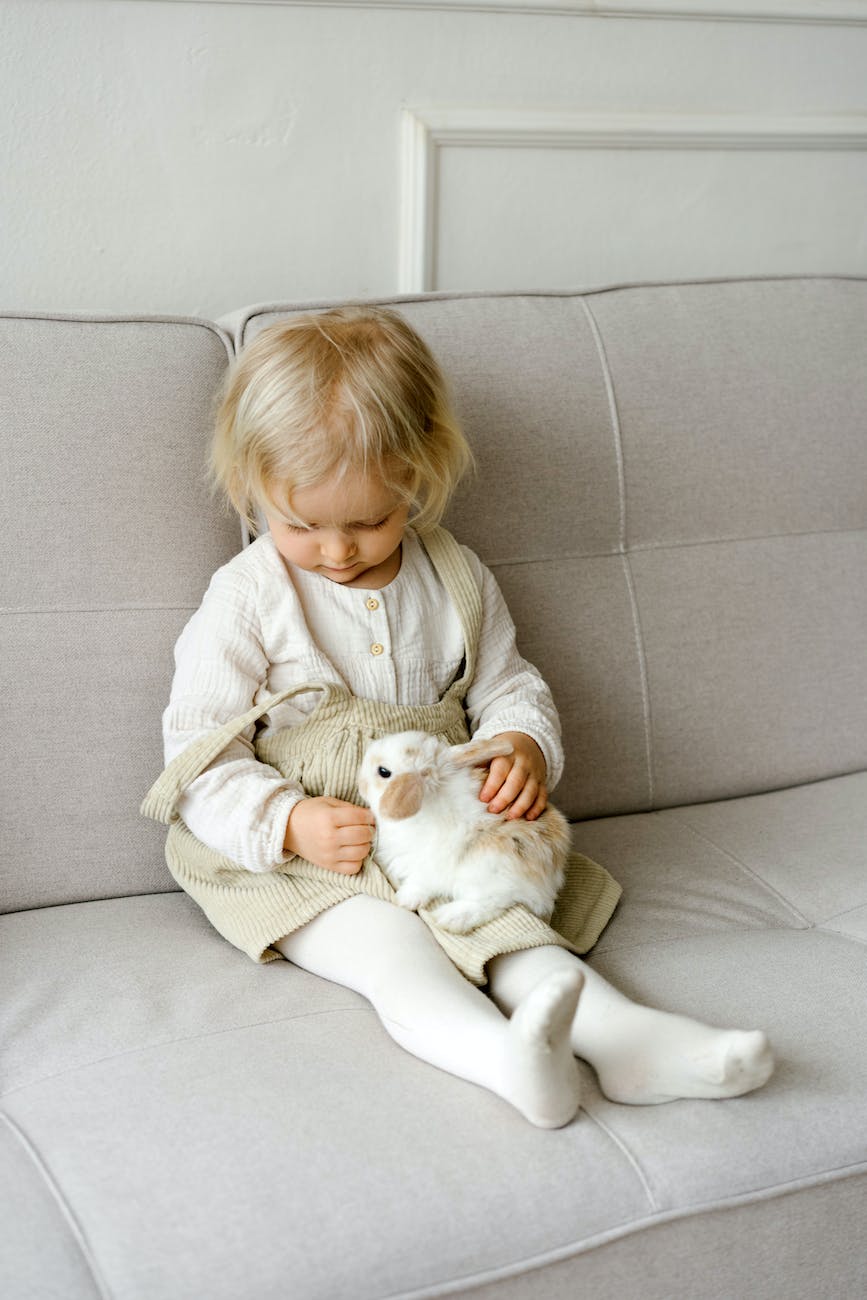 cute girl holding a rabbit while sitting on a sofa