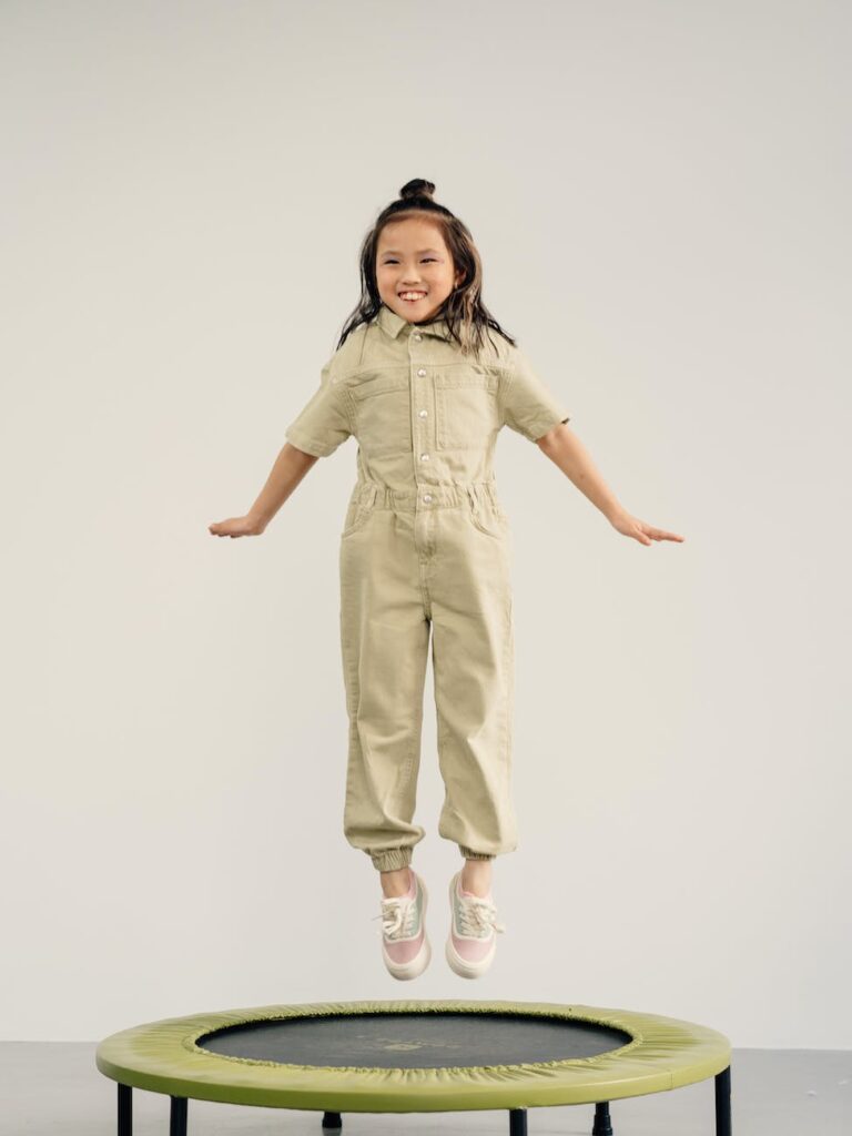 a happy little girl jumping on a trampoline