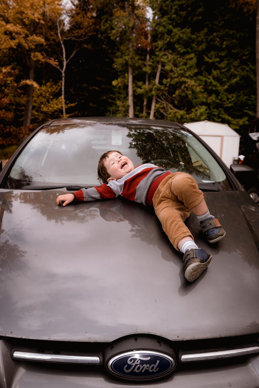 photo of boy lying down on car hood