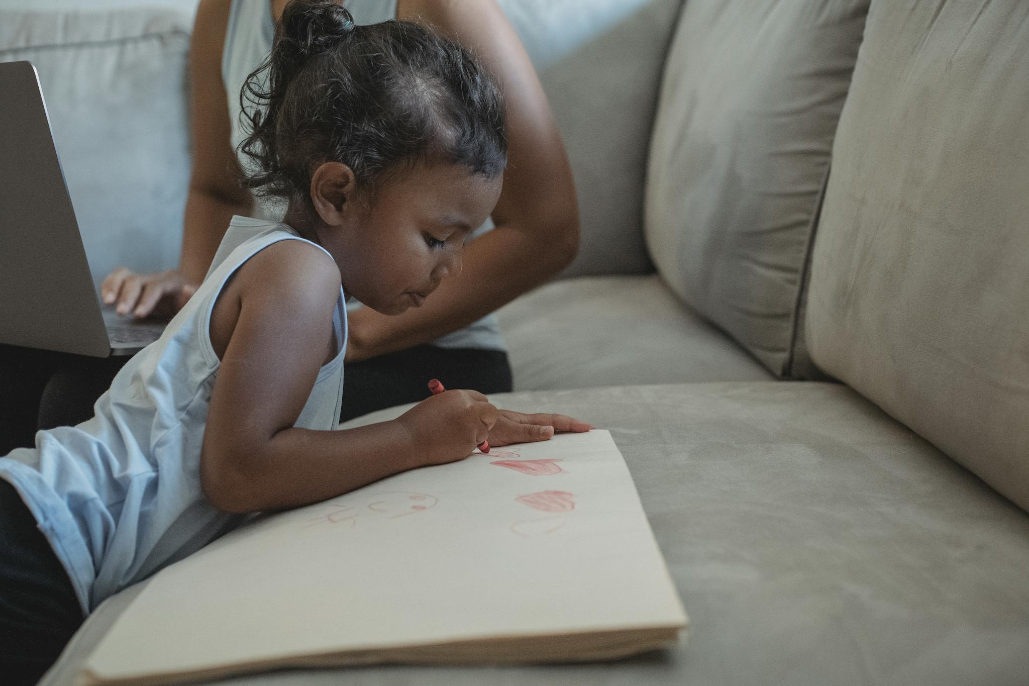 Concentrated ethnic girl drawing on paper